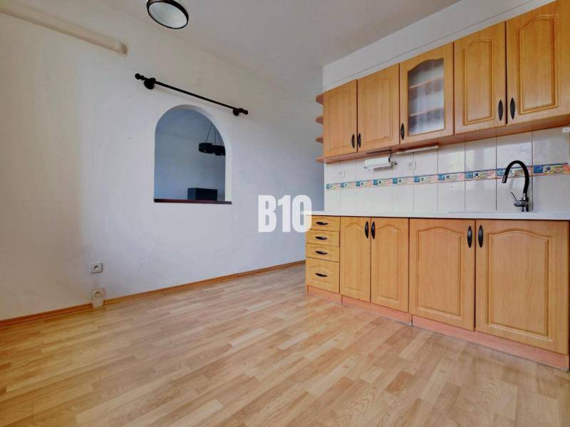 Kuchyně ve 3-pokojovém bytě s podlahou s dřevěným dekorem a vestavěnými skříňkami.