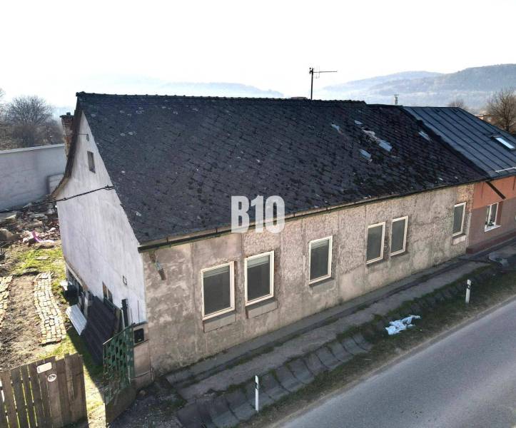 Rodinný dům v Bytči s opotřebovanou střechou a omítkou, vedle hlavní silnice.