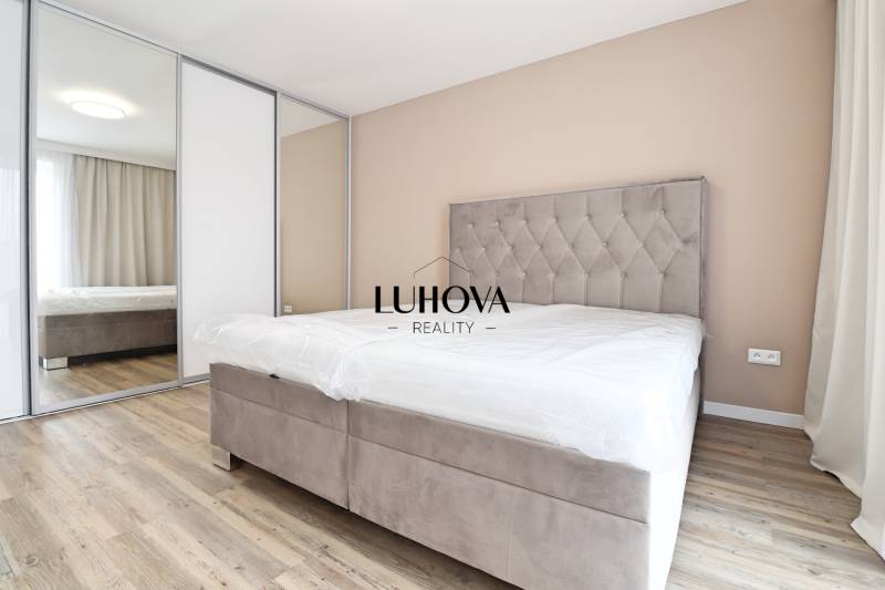 Ložnice v 3-pokojovém bytě s pohodlnou postelí, vestavěnou skříní a podlahou s dřevěným dekorem.