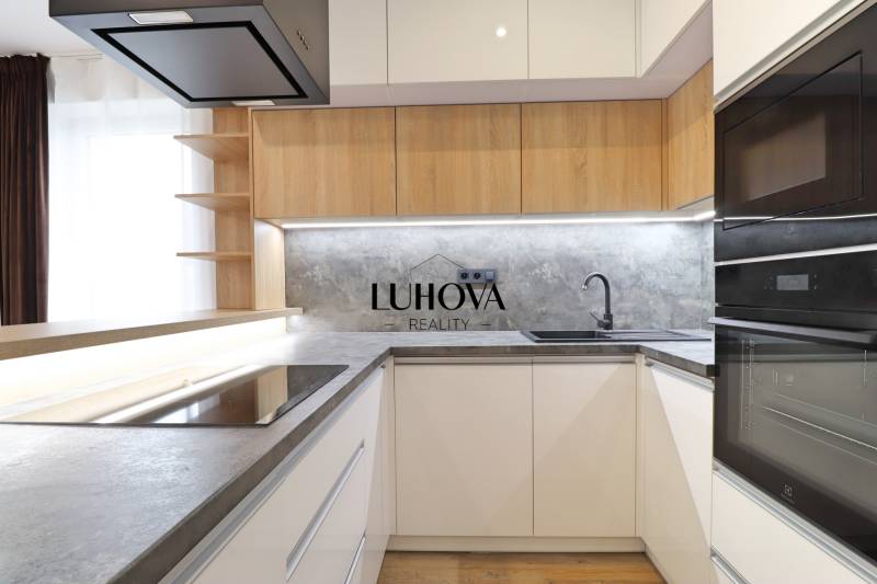 Kuchyně s hladkými liniemi a podlahou s dřevěným dekorem ve 3pokojovém bytě.