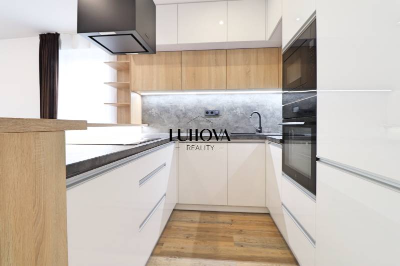 Kuchyně v 3-pokojovém bytě s bílými skříňkami a podlahou s dřevěným dekorem.