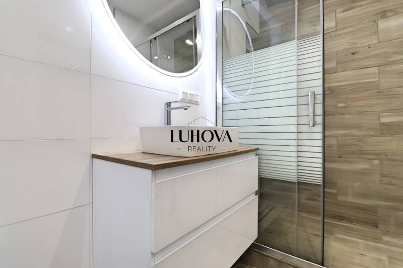 Koupelna s umyvadlem a sprchovým koutem v 3-pokojovém bytě, podlaha s dřevěným dekorem.