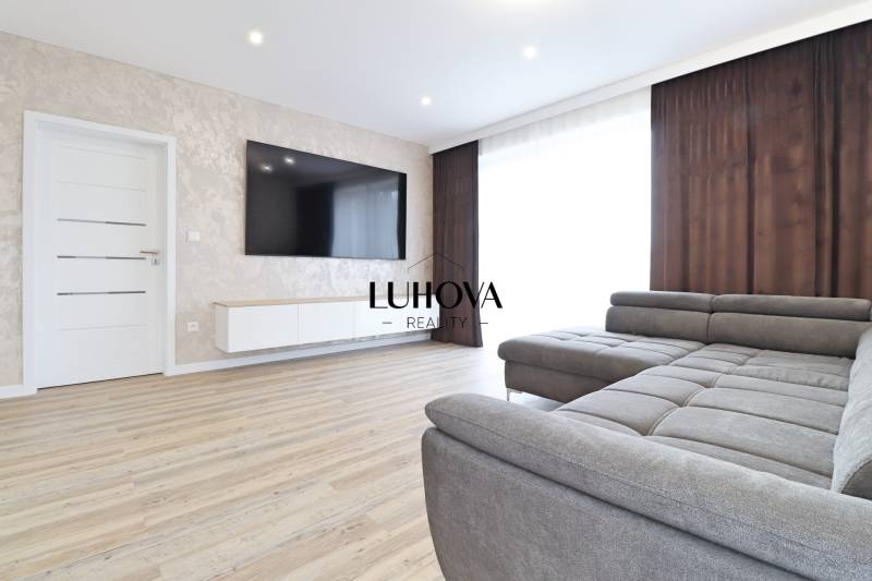 Obývací pokoj ve 3-pokojovém bytě s pohovkou a podlahou s dřevěným dekorem.