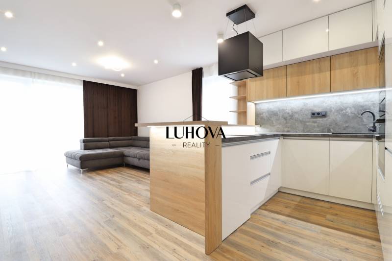 Interiér 3-pokojového bytu s kuchyní, sedačkou a podlahou s dřevěným dekorem.