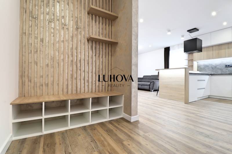 Interiér 3-pokojového bytu s podlahou s dřevěným dekorem, kuchyní a obývací částí.