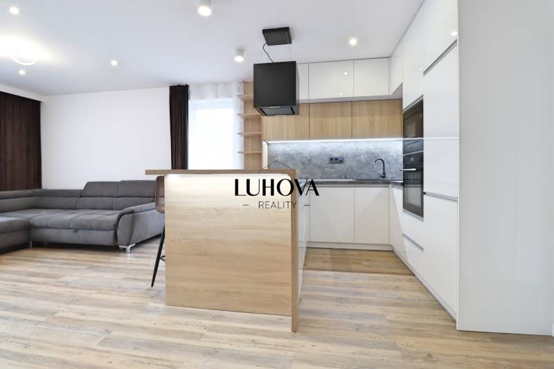 Obývací pokoj s kuchyní a podlahou s dřevěným dekorem ve 3pokojovém bytě.