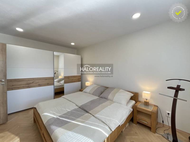 Světlá ložnice v 1-pokojovém bytě s podlahou s dřevěným dekorem a vestavěnou skříní.