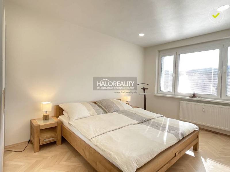 Světlá ložnice v 1-pokojovém bytě s podlahou s dřevěným dekorem a velkým oknem.