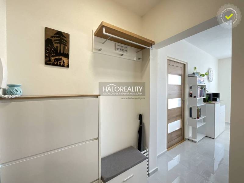 Interiér 1-pokojového bytu s věšákem, botníkem a poličkami u dveří.