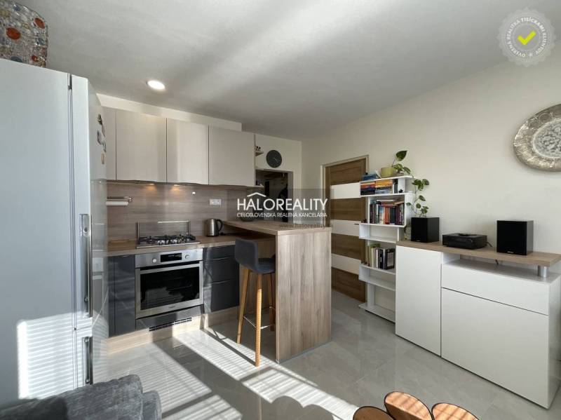 Kuchyně v 1-pokojovém bytě s prosvětleným interiérem a pultem na sezení.