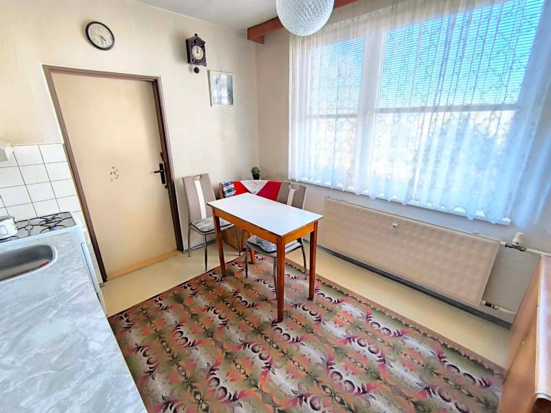 Kuchyně ve 3-pokojovém bytě s jídelním stolem, křesly a kobercem.