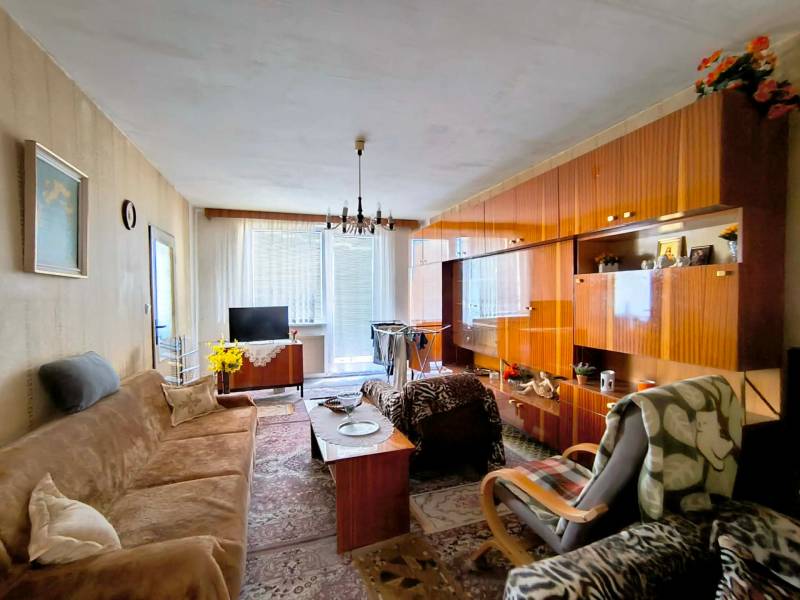 Obývací pokoj v 3pokojovém bytě s podlahou s dřevěným dekorem a sedací soupravou.