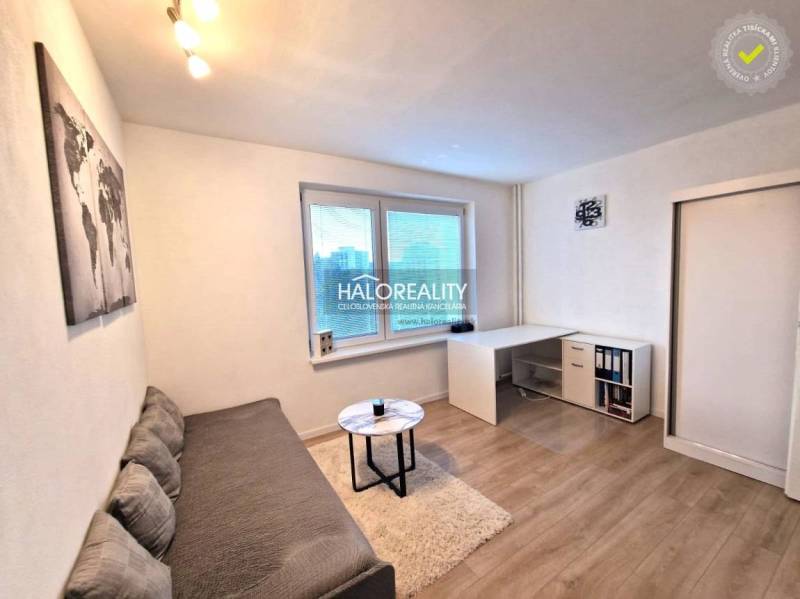 Obývací pokoj ve 3-pokojovém bytě s pohovkou, stolkem a podlahou s dřevěným dekorem.