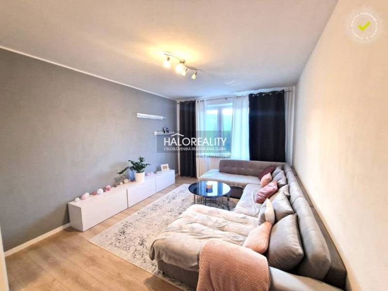 Obývací pokoj v 3pokojovém bytě s podlahou s dřevěným dekorem a rohovou sedačkou.