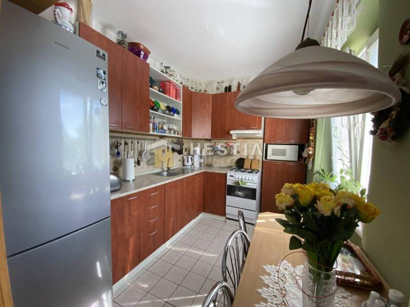 Rustikální kuchyně v 2pokojovém bytě s jídelním stolem a plnými policemi.