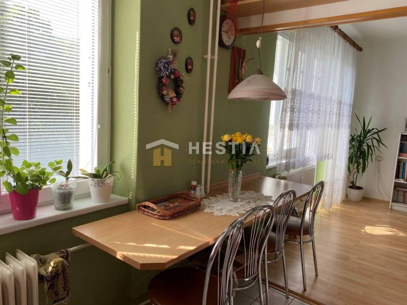 Jídelna s dřevěným dekorem, zelenými stěnami, květinami a stolem v dvoupokojovém bytě.