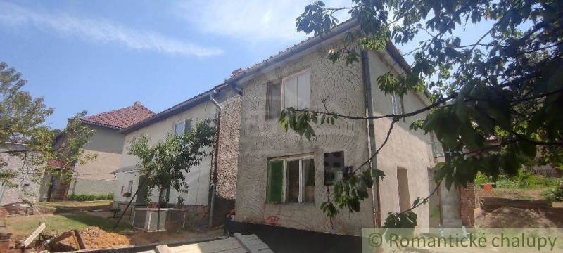 Rodinný dům v Šiatorské Bukovince, obklopený zelení a stromy, se šikmou střechou.