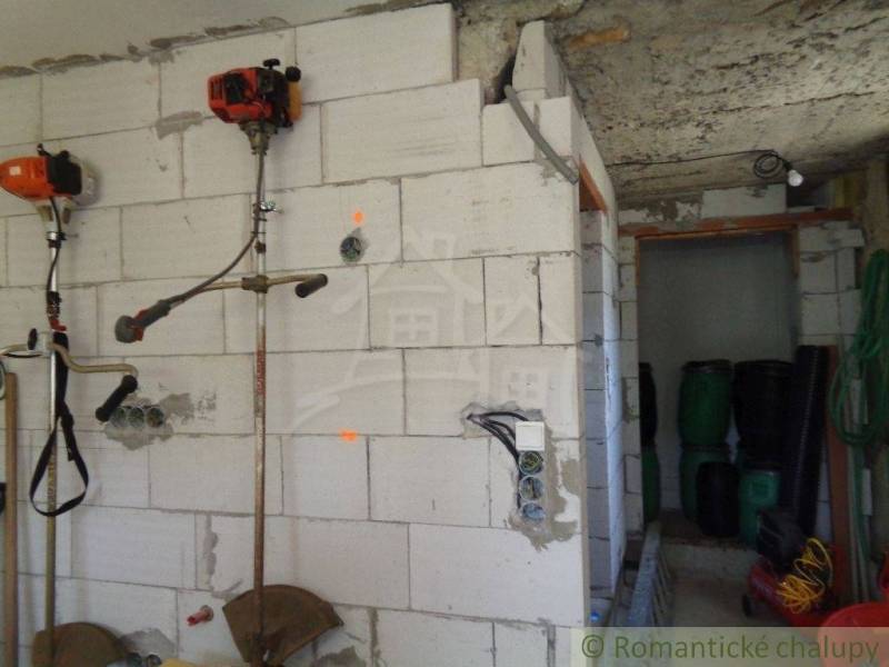 Interiér rodinného domu s nářadím na stěně a skladovacími sudy v Šiatorské Bukovince.