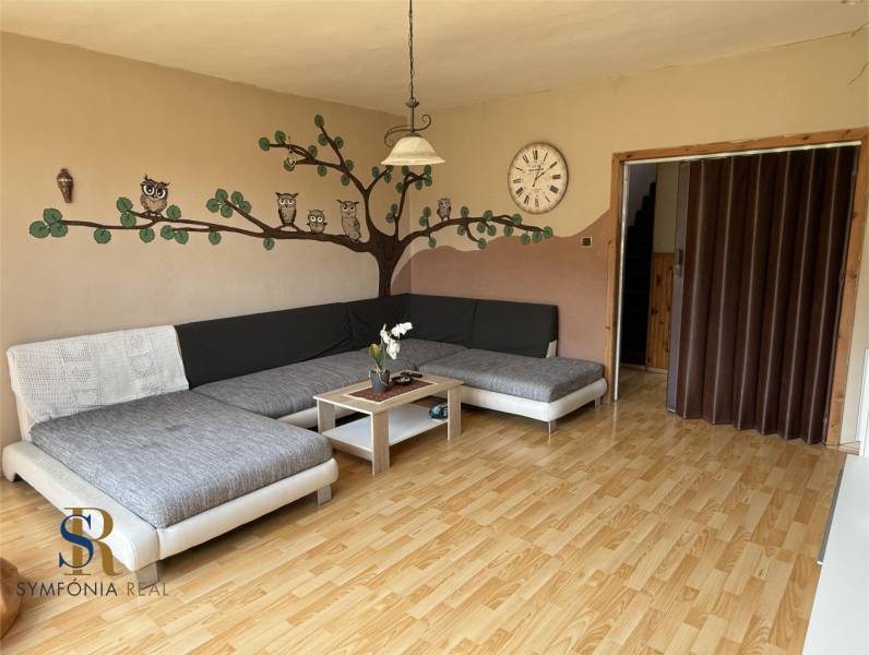 Obývací pokoj s pohovkou, dekorací sovy na stěně a podlahou s dřevěným dekorem.