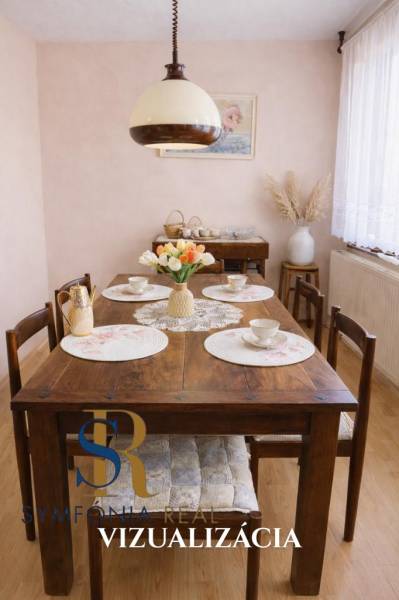 Jídelna rodinného domu s dřevěným stolem, dekorovaná květinami a porcelánem.