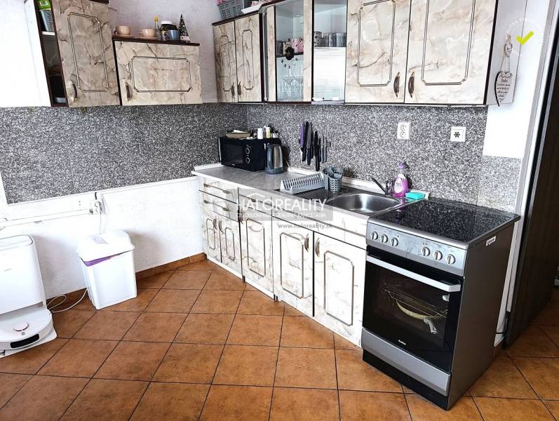 Kuchyně s dlažbou a kuchyňskou linkou v 2-pokojovém bytě.