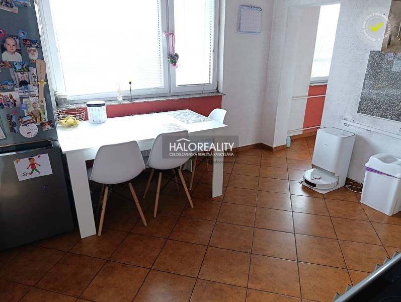 Jídelna v 2-pokojovém bytě s bílým stolem a hnědou podlahou.