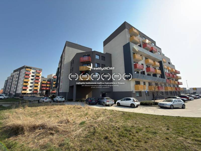 Bytové domy na Mikovíniho ulici v Trnavě s parkovištěm a zelenou plochou.