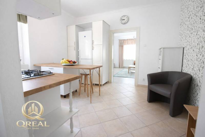 Kuchyně s barovým pultem v 1-pokojovém bytě a ovocem na stole.