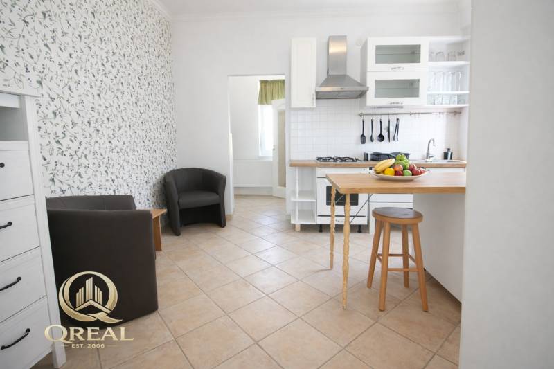 Kuchyně s barovým pultem, ovocem a křesly v 1-pokojovém bytě.