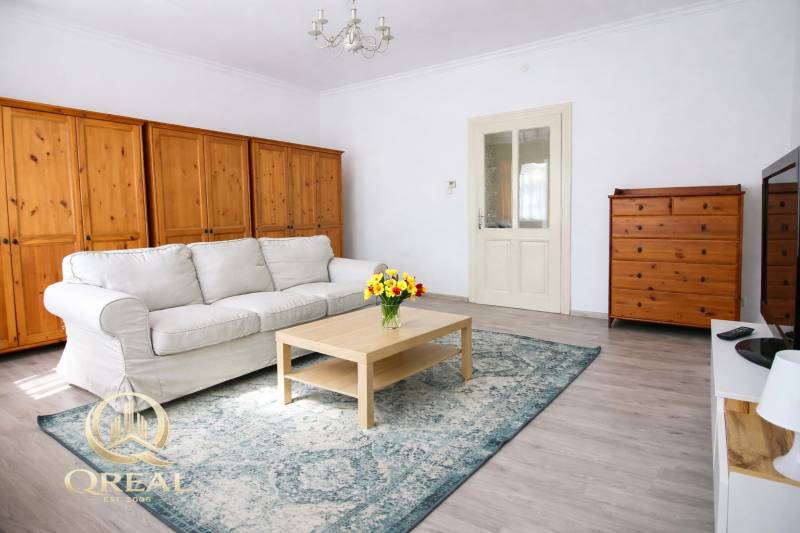 Světlý obývací pokoj s pohovkou, dřevěným nábytkem a podlahou s dřevěným dekorem.