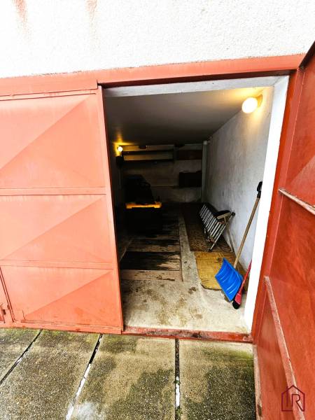 Garáž v rodinném domě v Kameňanech s otevřenými kovovými dveřmi a nářadím.