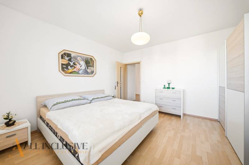 Ložnice s podlahou s dřevěným dekorem v rodinném domě a obrazem na stěně.