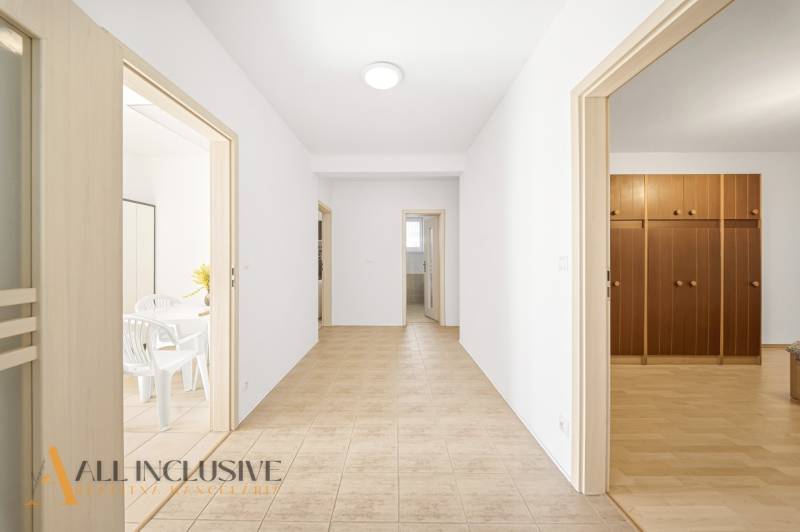 Chodba v rodinném domě s dveřmi do pokojů a dlažbou na podlaze.