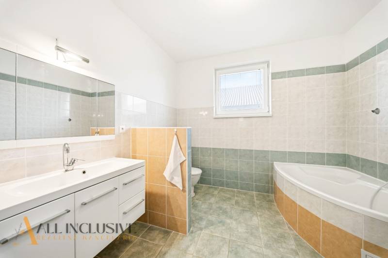 Koupelna s vanou, zrcadlem a úložným prostorem v rodinném domě.