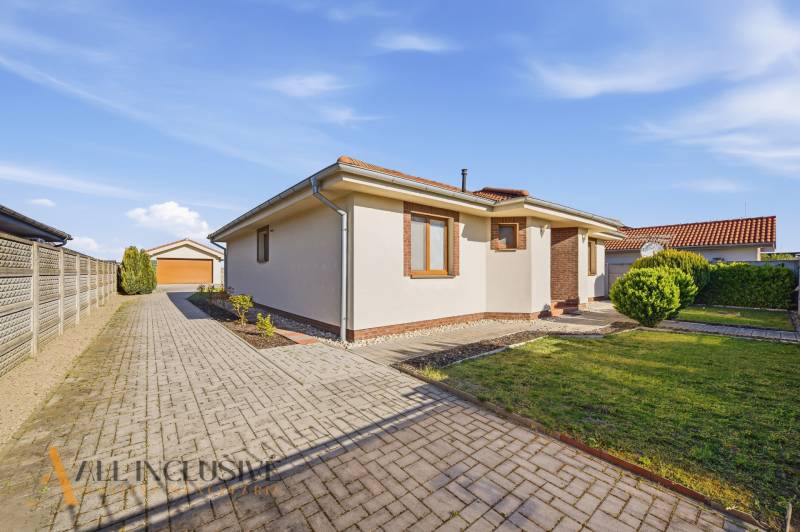 Rodinný dům v Kútnikách s dlážděným chodníkem a udržovanou zahradou.