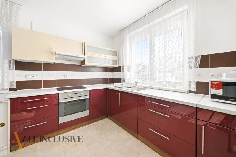 Kuchyně v rodinném domě s červenými skříňkami a spotřebiči.