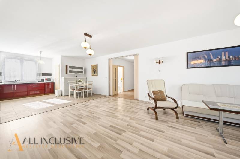 Světlý obývací pokoj s kuchyní, podlaha s dřevěným dekorem, jídelní kout.