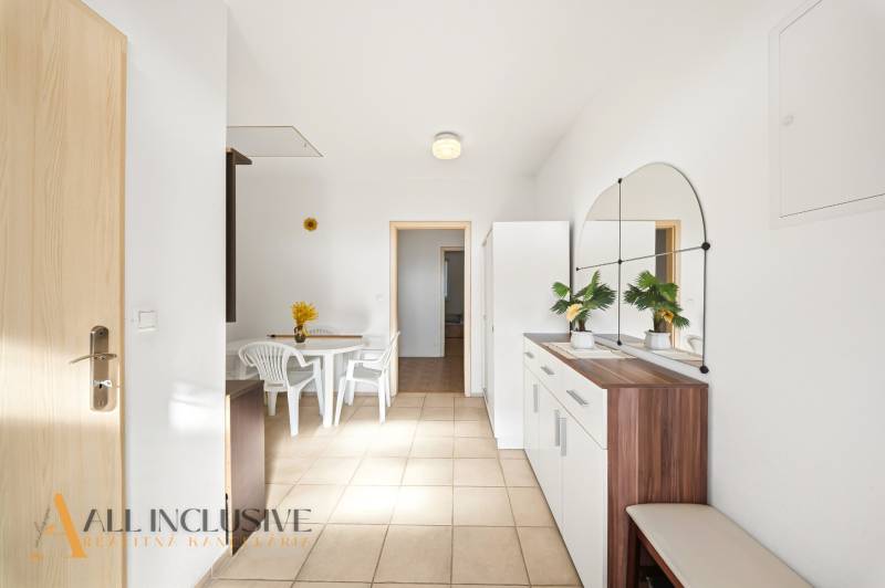 Interiér rodinného domu s bílým stolem a židlemi, s velkým zrcadlem na stěně.