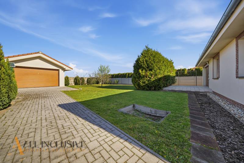 Rodinný dům v Kútnikách s garáží, trávníkem a zpevněnou přístupovou cestou.