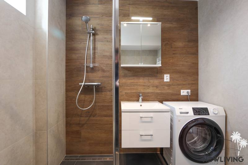 Koupelna v 3-pokojovém bytě s dřevěným dekorem a pračkou.