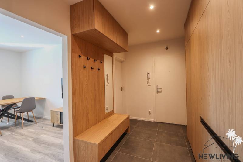 Vstupní hala 3pokojového bytu s podlahou z dlažby a dřevěným dekorem.