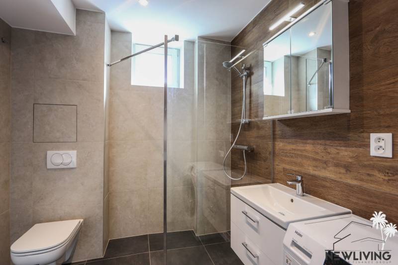 Koupelna v 3-pokojovém bytě s moderní sanitou a podlahou s dřevěným dekorem.