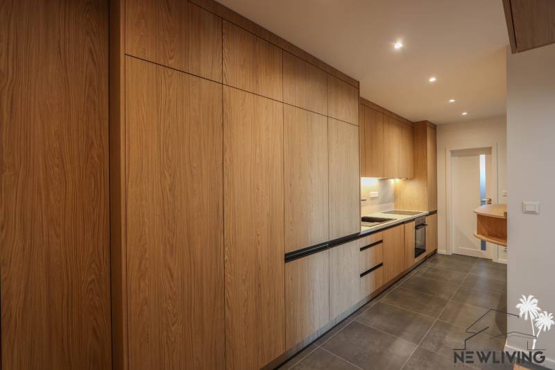 Kuchyně ve 3-pokojovém bytě s podlahou s dřevěným dekorem a vestavěnými spotřebiči.