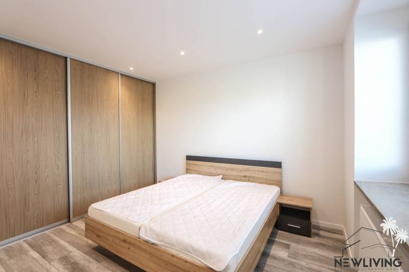 Ložnice v 3-pokojovém bytě s podlahou s dřevěným dekorem a velkou vestavěnou skříní.