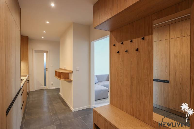Chodba s podlahou s dřevěným dekorem a šatníkovými skříněmi v 3-pokojovém bytě.