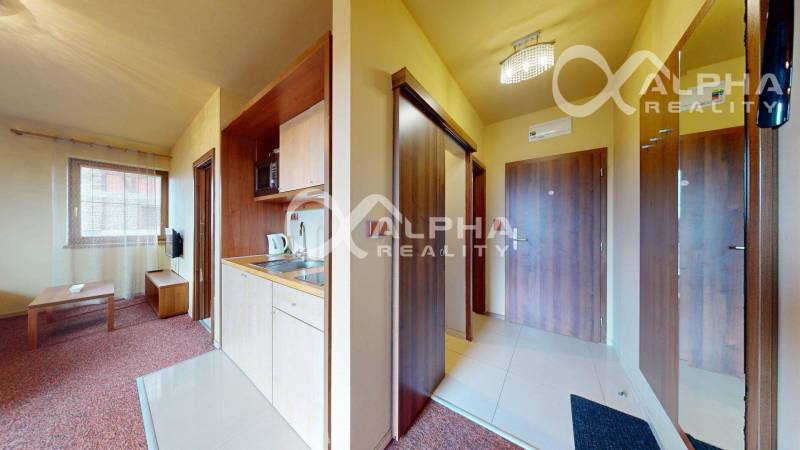 Interiér 2-pokojového bytu s kuchyňským koutem a obývacím pokojem s televizorem.