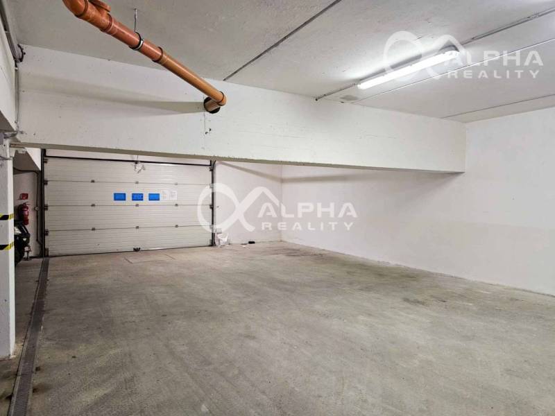 Garáž v 2-pokojovém bytě, s betonovou podlahou a rolovací bránou.
