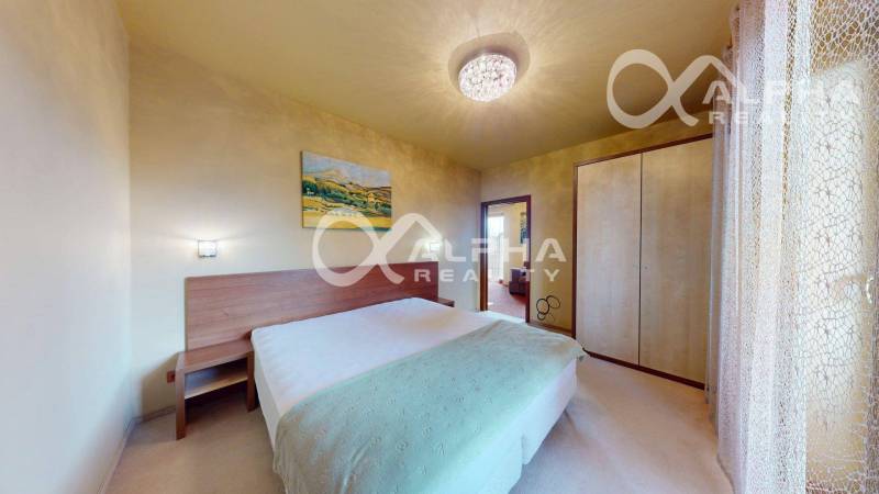 Ložnice v 2pokojovém bytě s postelí, skříní a obrazem na stěně.