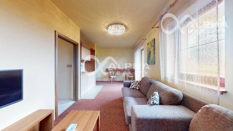 Obývací pokoj v 2-pokojovém bytě s pohovkou a jídelním stolem.