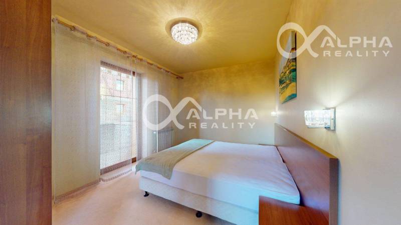 Ložnice v 2-pokojovém bytě se závěsy a lustrem, postelí a nočními stolky.